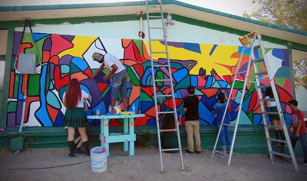 Miguel junto con alumnos realizando mural colectivo